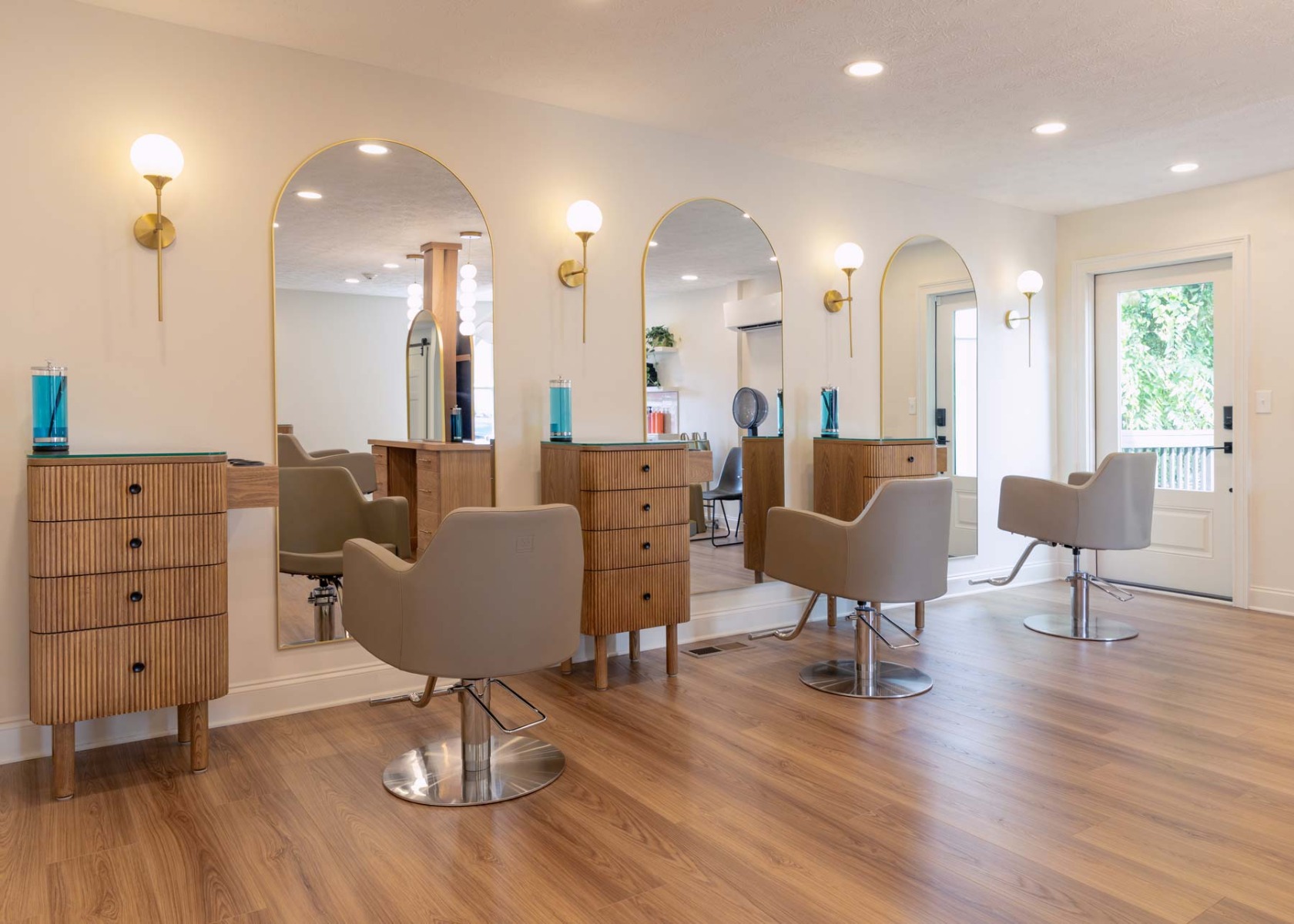 J. Italia Salon interior view of three salon stations outfitted with styling chairs, storage and arched mirrors